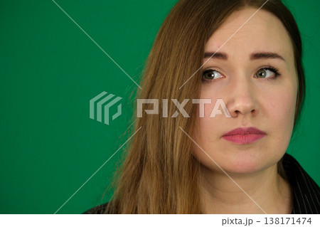 Woman volunteer in shirt with thoughtful expression against isolated green background wall reflects contemplation and purpose. Woman volunteer in shirt with thoughtful expression against isolated green background wall reflects contemplation and purpose. 138171474