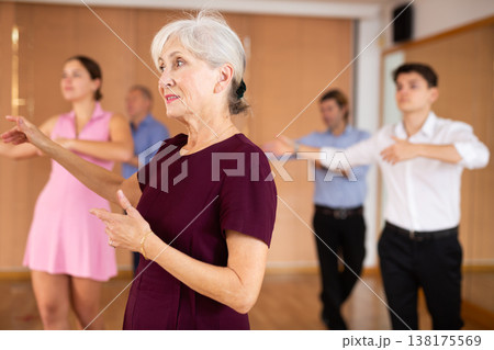 Cheerful elderly female dancer practicing ballroom dances in ballroom Cheerful elderly female dancer practicing ballroom dances in ballroom 138175569