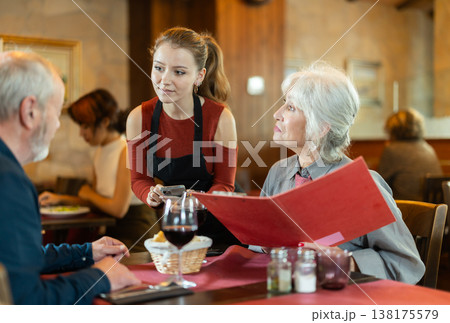 Young waitress taking order from elderly couple in restaurant Young waitress taking order from elderly couple in restaurant 138175579