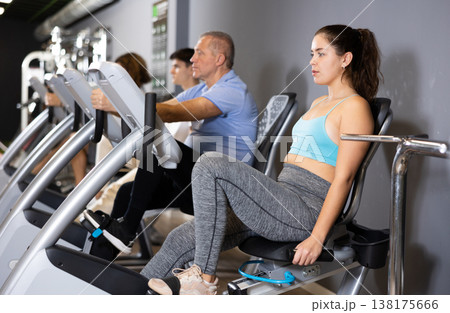 Young girl working out on stationary bicycle in gym Young girl working out on stationary bicycle in gym 138175666