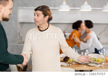 Men shaking hands while greeting each other before festive dinner Men shaking hands while greeting each other before festive dinner 138175727