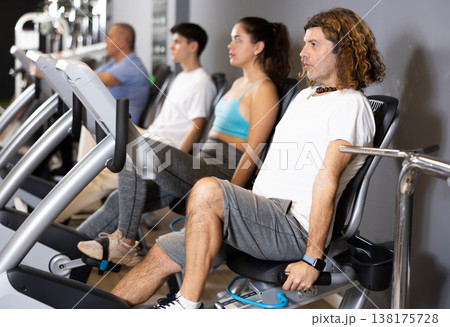 Motivated man doing cardio workout on exercise bike in gym Motivated man doing cardio workout on exercise bike in gym 138175728