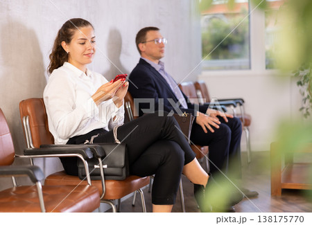 Young woman sitting in line at reception with phone Young woman sitting in line at reception with phone 138175770