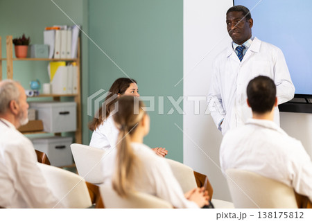 African male doctor stands with a remote control in his hands, he gives a lecture 138175812