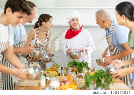 Amiable senior female chef running group culinary courses 138175817