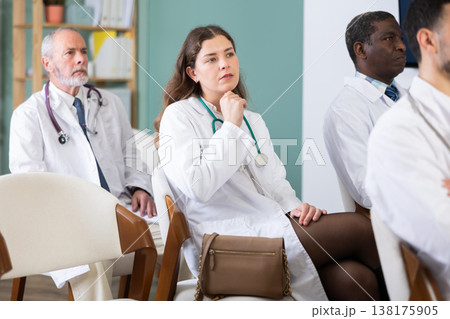 Girl doctor student at courses meeting listens to teacher and look at speaker Girl doctor student at courses meeting listens to teacher and look at speaker 138175905