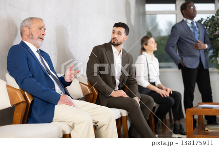 Young and elderly men talking while waiting in job interview queue Young and elderly men talking while waiting in job interview queue 138175911