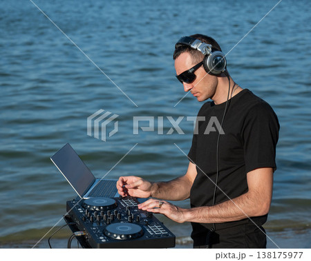 Caucasian man works as a DJ on the beach.  138175977