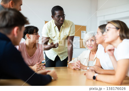 Friendly African American English tutor giving language courses to group of adults Friendly African American English tutor giving language courses to group of adults 138176026