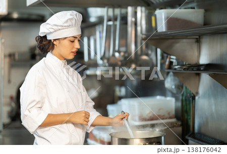 Young female cook preparing dish in restaurant kitchen 138176042