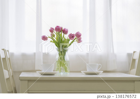 ダイニングテーブルに置かれたティーカップとチューリップの花瓶 138176572