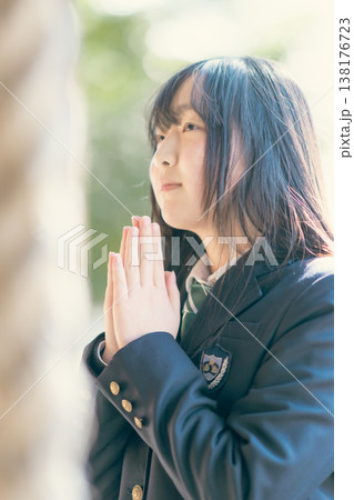 神社で静かに目を閉じ手を合わせ祈る制服姿の女子高生 138176723