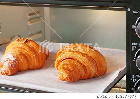 Fresh croissants baking in an oven during morning hours in a kitchen setting Fresh croissants baking in an oven during morning hours in a kitchen setting 138177677