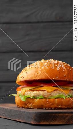 Burger with sesame seed bun on cutting board in kitchen setting during daylight Burger with sesame seed bun on cutting board in kitchen setting during daylight 138177726