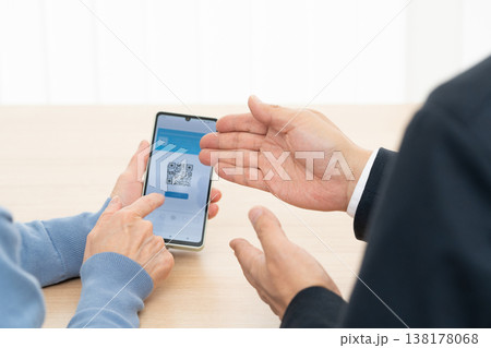 スマホアプリの使い方の説明を受けるシニア女性 138178068