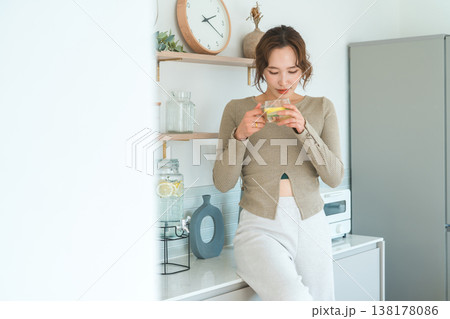 キッチンカウンターでデトックスウォーターを飲む女性 キッチンカウンターでデトックスウォーターを飲む女性 138178086