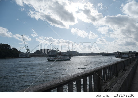 港を進む船とクレーンが並ぶ水辺の風景と青空 港を進む船とクレーンが並ぶ水辺の風景と青空 138178230