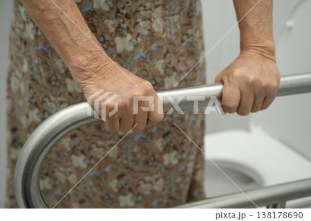 Asian elderly woman patient use toilet support rail in bathroom. Asian elderly woman patient use toilet support rail in bathroom. 138178690