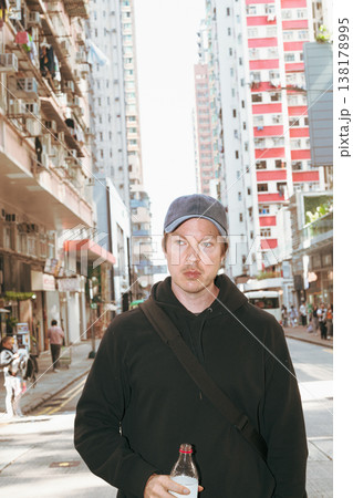 Caucasian Man Holding Bottle on Hong Kong City Street 138178995