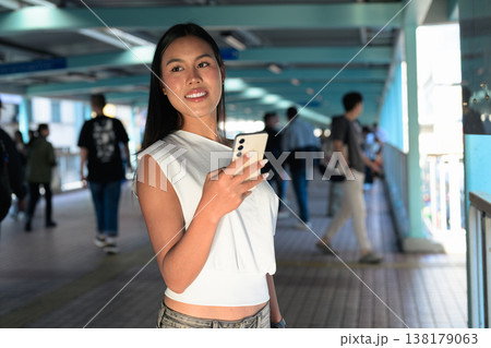 Thai Woman Using Smartphone on Hong Kong Pedestrian Walkway 138179063