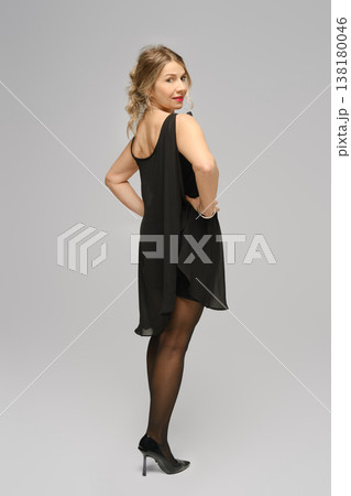 Woman in a black dress posing in a studio with a plain background in the afternoon 138180046