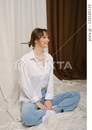 A young woman sits on the floor in a studio 138180110