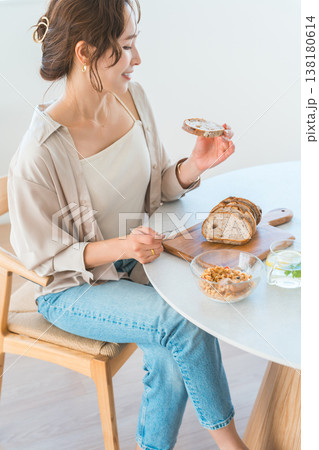 ダイニングテーブルで朝食をとダイニングテーブルで朝食をとる若いアジア人女性る若いアジア人女性 ダイニングテーブルで朝食をとダイニングテーブルで朝食をとる若いアジア人女性る若いアジア人女性 138180614