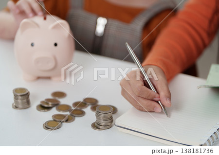 Parent writing financial notes while child saves money 138181736