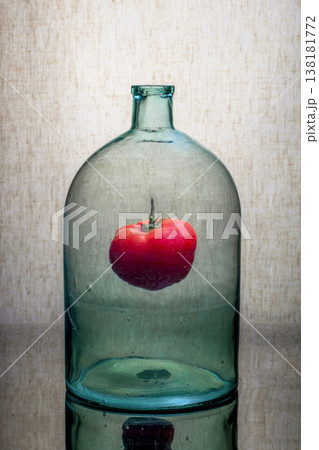 Still life with a glass jar and a tomato inside Still life with a glass jar and a tomato inside 138181772