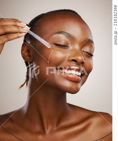 Skincare, woman and smile with dropper on studio background for wellness in cosmetics, beauty or serum. African, person or model by happy, face or relaxed for facial treatment for anti aging oil 138182366