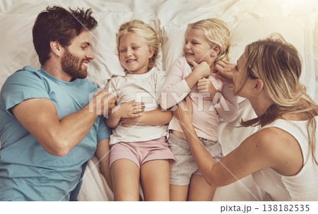 Family, children and parents in bed with smile, happiness and playing. Morning, tickle and funny with mom, dad and girls in bedroom, home and bonding together in top view, playful and affectionate 138182535