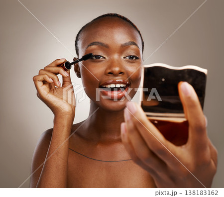 Black woman, mascara with brush and mirror, makeup and shine with beauty isolated on brown background. Eyelash extension, wand and skin glow with cosmetology, transformation and wellness in studio 138183162