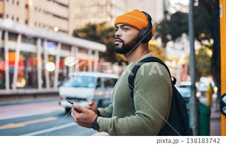 Phone, headphones of student and thinking in city, listening to music or sound . Smartphone, radio and serious man in street for streaming podcast, typing on social media and reading email to travel 138183742