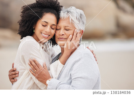 Women, mother and daughter on beach, hugging and smiling in embrace, love and happiness. Family vacation, joy and bonding for retirement, resting and relaxation on ocean, enjoying and quality time 138184036