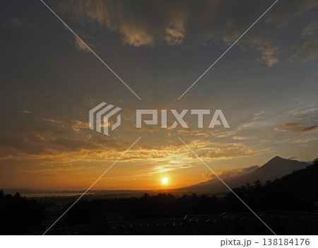 磐梯山と猪苗代湖の間に沈む夕日。オレンジ色の太陽と雲にシルエットの山が印象的で綺麗だ。 磐梯山と猪苗代湖の間に沈む夕日。オレンジ色の太陽と雲にシルエットの山が印象的で綺麗だ。 138184176