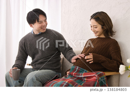 ソファに座ってくつろぐ若い夫婦 妊婦さん ソファに座ってくつろぐ若い夫婦 妊婦さん 138184803