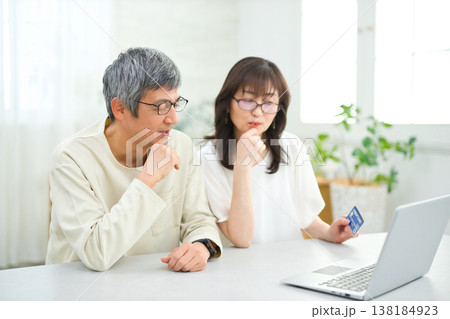 リビングでパソコンとカードを見る60代の夫婦 138184923