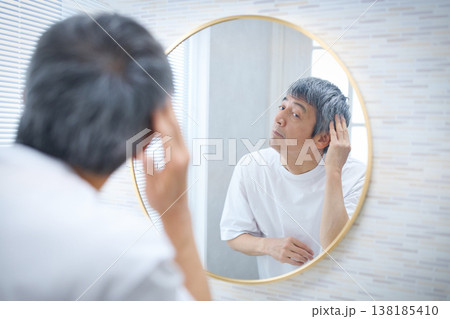鏡を見て白髪を気にする60代の男性 138185410