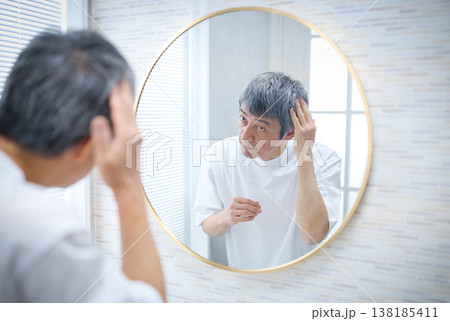 鏡を見て白髪を気にする60代の男性 鏡を見て白髪を気にする60代の男性 138185411