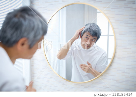 鏡を見て白髪を気にする60代の男性 鏡を見て白髪を気にする60代の男性 138185414