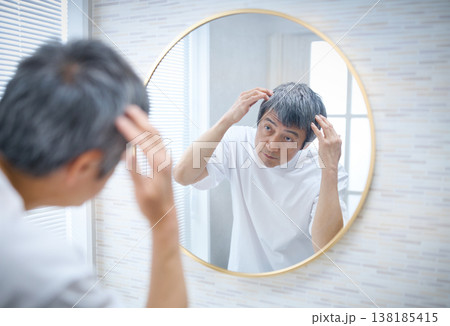 鏡を見て白髪を気にする60代の男性 鏡を見て白髪を気にする60代の男性 138185415