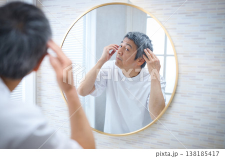 鏡を見て白髪を気にする60代の男性 138185417
