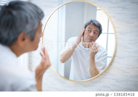鏡を見て白髪を気にする60代の男性 138185418