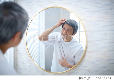 鏡を見て白髪を気にする60代の男性 鏡を見て白髪を気にする60代の男性 138185423