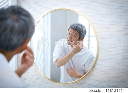 鏡を見て白髪を気にする60代の男性 138185424