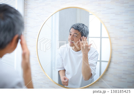 鏡を見て白髪を気にする60代の男性 138185425