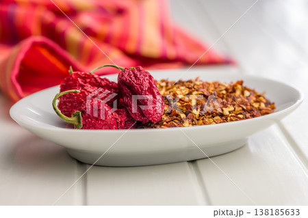 Dried Red Chili Peppers and Crushed Chili Flakes on White Plate. Spicy Seasoning Ingredient for Cooking 138185633