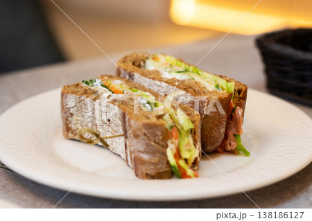 Casual dining scene with hearty sandwich served on ceramic dish in warm cafe lighting Casual dining scene with hearty sandwich served on ceramic dish in warm cafe lighting 138186127