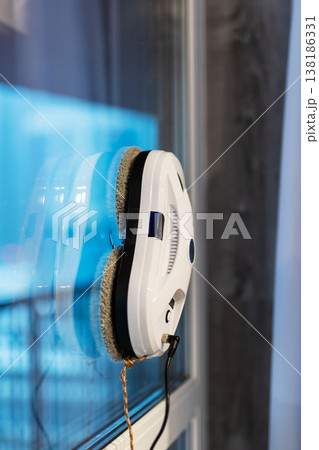 Automated window cleaning device with magnetic pads and tether in urban maintenance operation 138186331