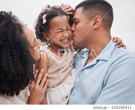 Family, beach and mother with father, girl and vacation with sunshine, bonding and weekend break. Parents, mama and dad with embrace, kid or child outdoor with happiness, seaside holiday and cheerful 138186911